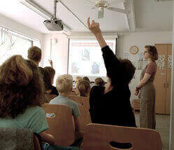 Ingeborg Lambert hält einen Vortrag im Klassenzimmer der Grundschule, ein Schüler meldet sich.