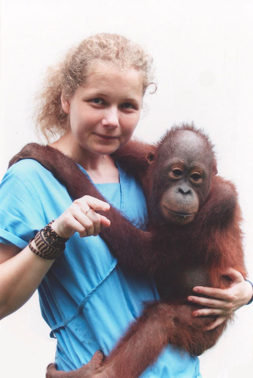 Julia Cissewski hält einen jungen Orang-Utan auf dem Arm und lächelt in die Kamera.